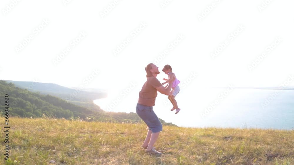Dad and his little daughter are enjoying the sunset on the shore of mountain lake. Dad and his little daughter are enjoying the sunset on the shore of mountain lake.