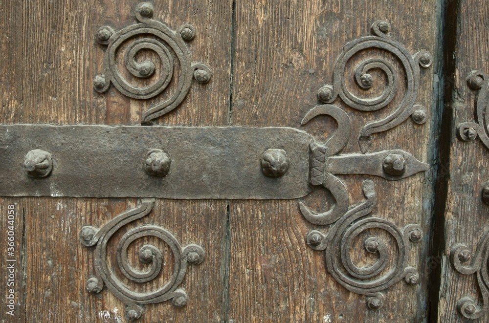 Large grungy wooden gate with metal forged design elements. Weathered wood, historical place in Spain, Europe Large grungy wooden gate with metal forged design elements. Weathered wood, historical place in Spain, Europe