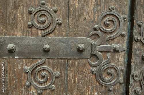 Large grungy wooden gate with metal forged design elements. Weathered wood, historical place in Spain, Europe photo