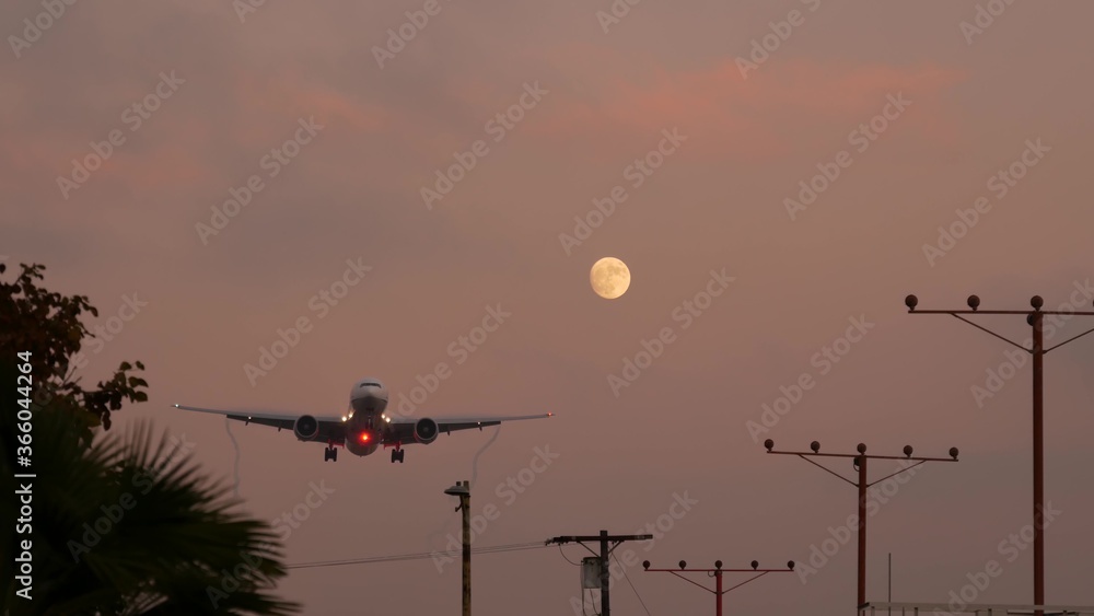 Airplane landing in LAX airport at sunset, Los Angeles, California USA. Passenger flight or cargo plane silhouette, dramatic cloudscape. Aircraft arrival to airfield. International transport flying Airplane landing in LAX airport at sunset, Los Angeles, California USA. Passenger flight or cargo plane silhouette, dramatic cloudscape. Aircraft arrival to airfield. International transport flying