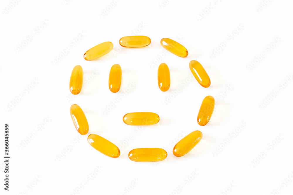 Smiley face from gelatin softgels Capsules of Omega-3 fats on white background. Eicosapentaenoic acid and fish oil. Organic dietary supplements concept. Selective focus, backlight Smiley face from gelatin softgels Capsules of Omega-3 fats on white background. Eicosapentaenoic acid and fish oil. Organic dietary supplements concept. Selective focus, backlight