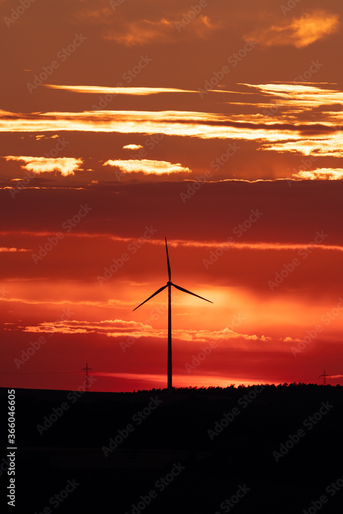 Obraz premium A silhouette of a distant windmill in front of a buring sky