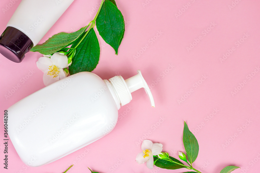 Top view of white plastic cosmetic container for moisturizing cream as a mock up with bright fresh jasmine flowers on pink background with copy space. Body and skin care and beauty concept. Top view of white plastic cosmetic container for moisturizing cream as a mock up with bright fresh jasmine flowers on pink background with copy space. Body and skin care and beauty concept.
