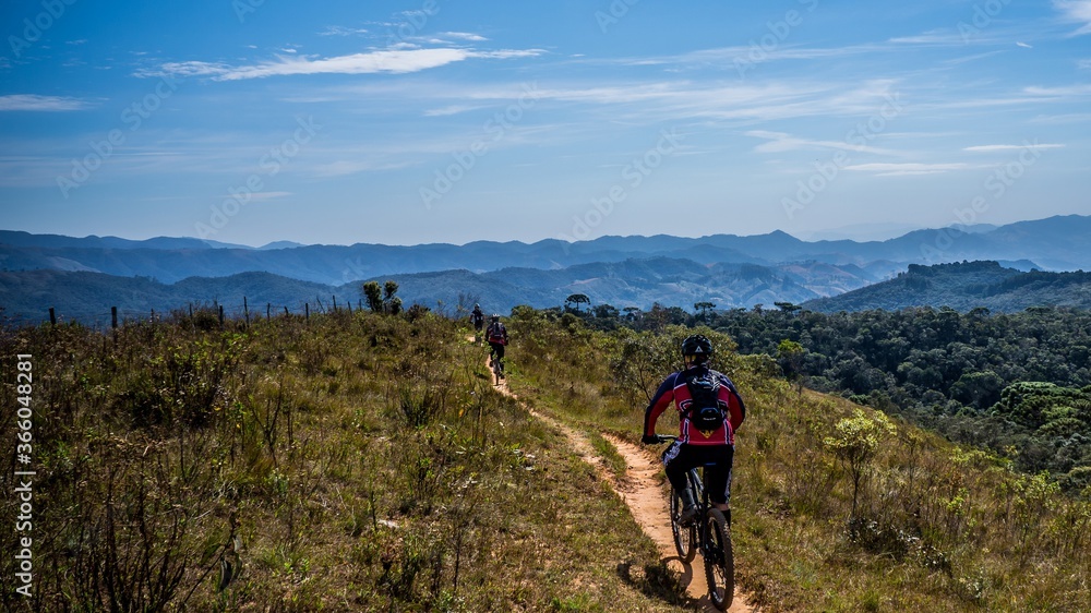 friends pedaling their mountain bikes on a singletrack on top of the mountain