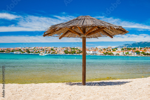 Adriatic sea shore in Croatia on Pag island, parasol on beautiful sand beach in town of Novalja