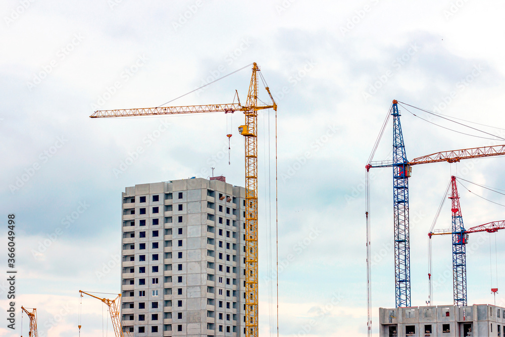 Construction site with the high cranes building a grey block house in the city. Construction site with the high cranes building a grey block house in the city.