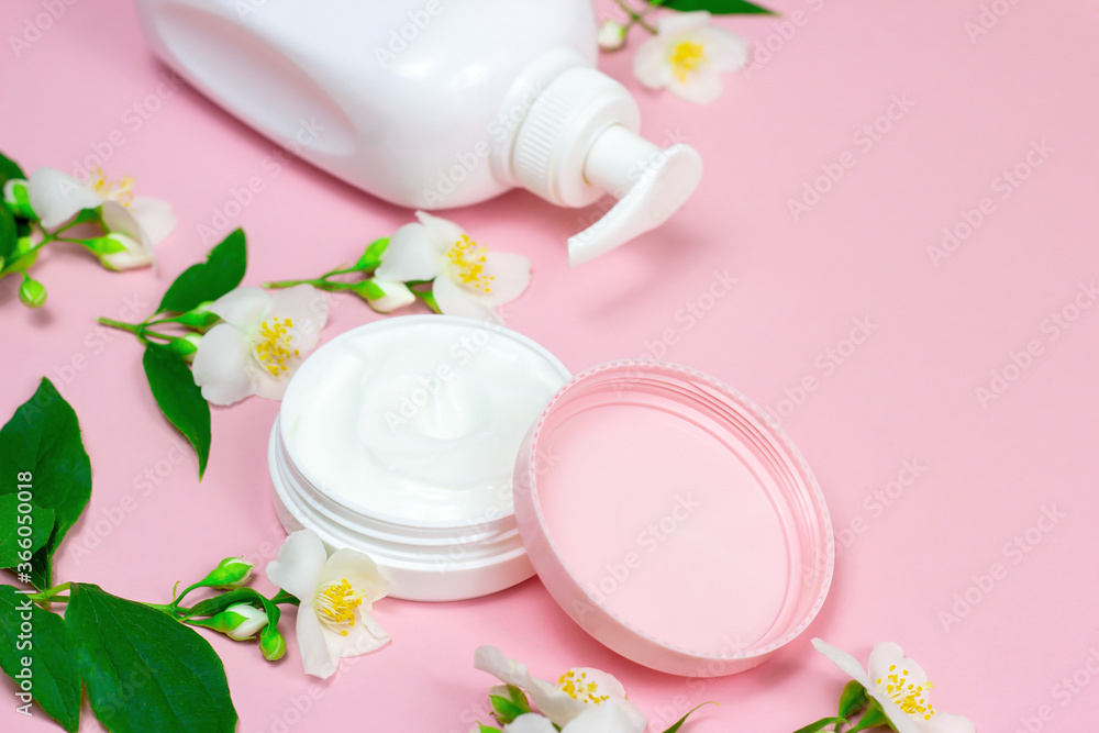 White plastic cosmetic container for moisturizing cream as a mock up with bright fresh jasmine flowers on light pink background with copy space White plastic cosmetic container for moisturizing cream as a mock up with bright fresh jasmine flowers on light pink background with copy space