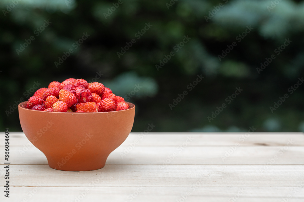 A clay cup with red, juicy strawberries stands on a wooden table A clay cup with red, juicy strawberries stands on a wooden table