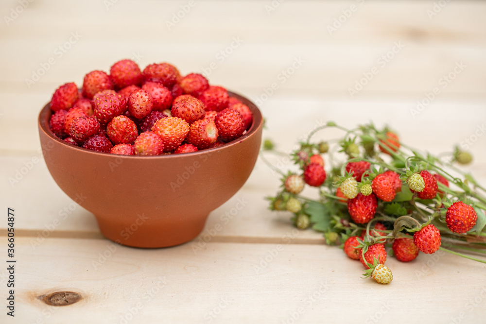 A clay cup with red, juicy strawberries stands on a wooden table A clay cup with red, juicy strawberries stands on a wooden table