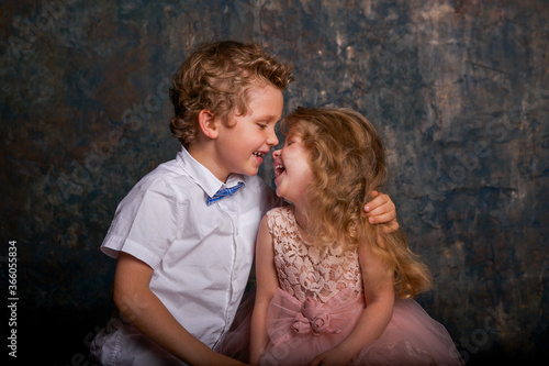 Young toothless boy and little girl laughing against blue and gold wall. Emotions. Copy space.