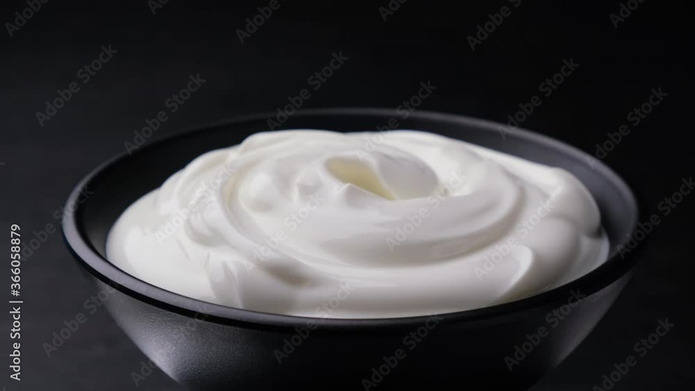 Bowl of sour cream on black background, greek yogurt, 4K UHD video footage Bowl of sour cream on black background, greek yogurt, 4K UHD video footage