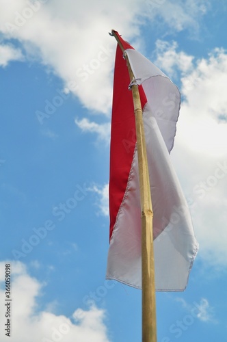 Indonesian flag waving in the wind against a blue sky and clouds. Red and white flag. Independence of Indonesia