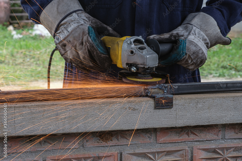 Men who are using grinding tools on steel of window Men who are using grinding tools on steel of window