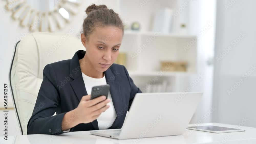 African Businesswoman using Smartphone and Laptop in Office African Businesswoman using Smartphone and Laptop in Office