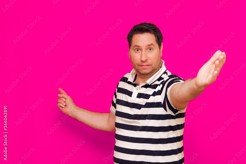 Joyful man in striped t-shirt gesturing index finger hand on camera isolated over magenta background Joyful man in striped t-shirt gesturing index finger hand on camera isolated over magenta background