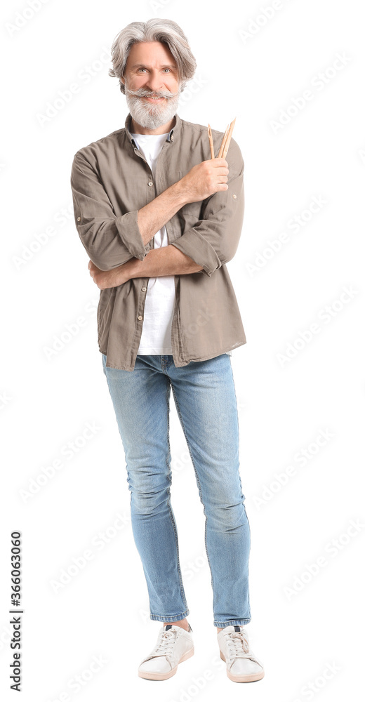 Fototapeta premium Smiling senior man with gray hair and beard holding pencils, creative hobby and artistic expression