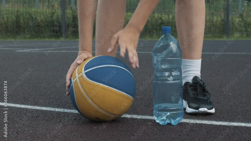 Sweaty tired Female Basketball player taking fresh cold water from plastic bottle and then