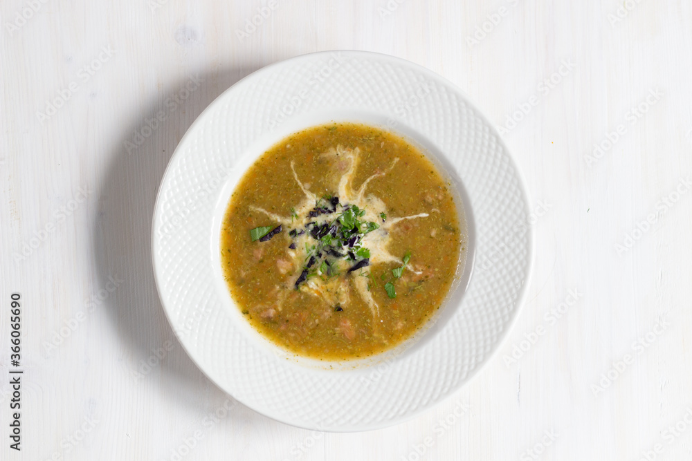 bowl of vegetable cream soup with sour cream and herbs on white wooden table bowl of vegetable cream soup with sour cream and herbs on white wooden table
