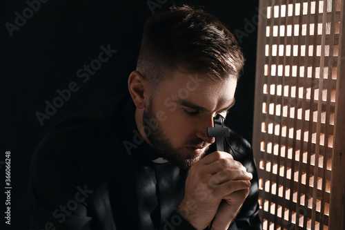 Fototapeta Young priest in confession booth