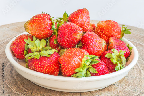 Strawberries in a plate on the table on a white background.