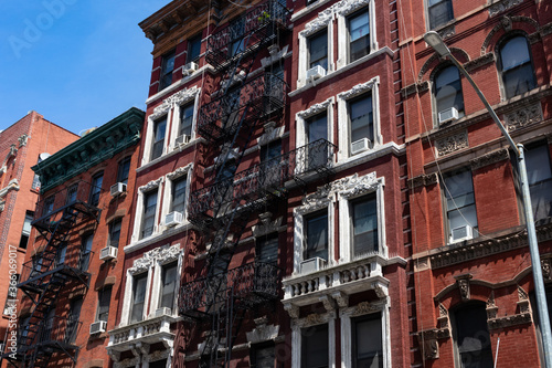 Row of Old Red Brick Residential Buildings with Fire Escapes on the Lower East Side of New York City © James
