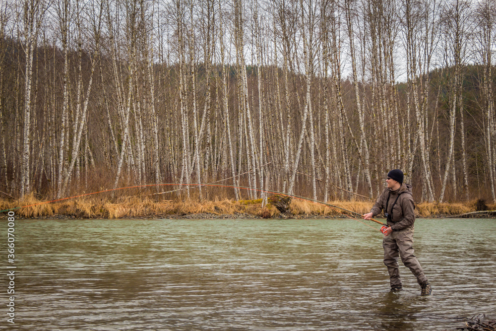 A fly fisherman hooked into a big fish with the rod bent, on the Kalum River, Skeena Region, British Columbia, Canada