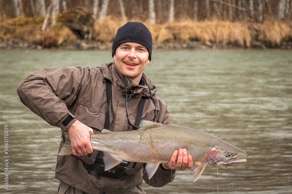 A fisherman holding up a steelhead on the Kalum River, Skeena Region, British Columbia, Canada A fisherman holding up a steelhead on the Kalum River, Skeena Region, British Columbia, Canada