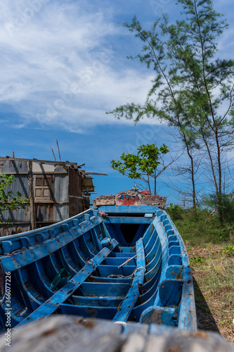 A old and broken wooden fishing boat on the beach in the coastal grass