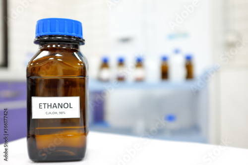 Selective focus of ethanol or ethyl alcohol brown amber glass bottle inside a laboratory. Blurred background with copy space.