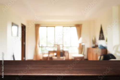 Empty wooden desk space and blurry background of home window for product display montage.