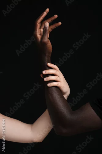 Obraz Hands of Caucasian woman and African-American man on dark background. Racism concept
