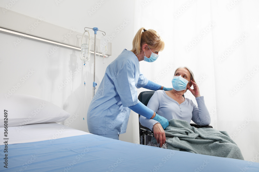 Fototapeta premium nurse take comfort elderly woman in wheelchair wearing surgical protective medical masks in hospital room, concept of isolation from corona virus covid 19