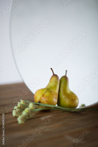 Fresh ripe organic yellow pear stands on a rustic wooden table near a round mirror. Femininity. the concept of care. Selective focus. Space for text