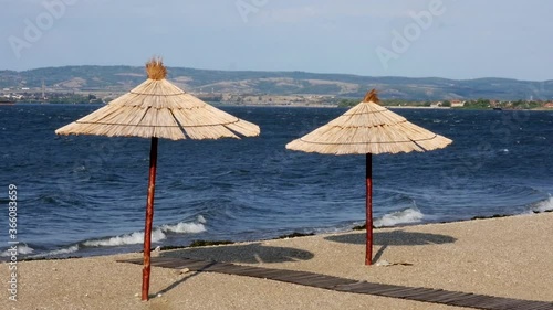 Two reed umbrellas on the bank of the river beach photo