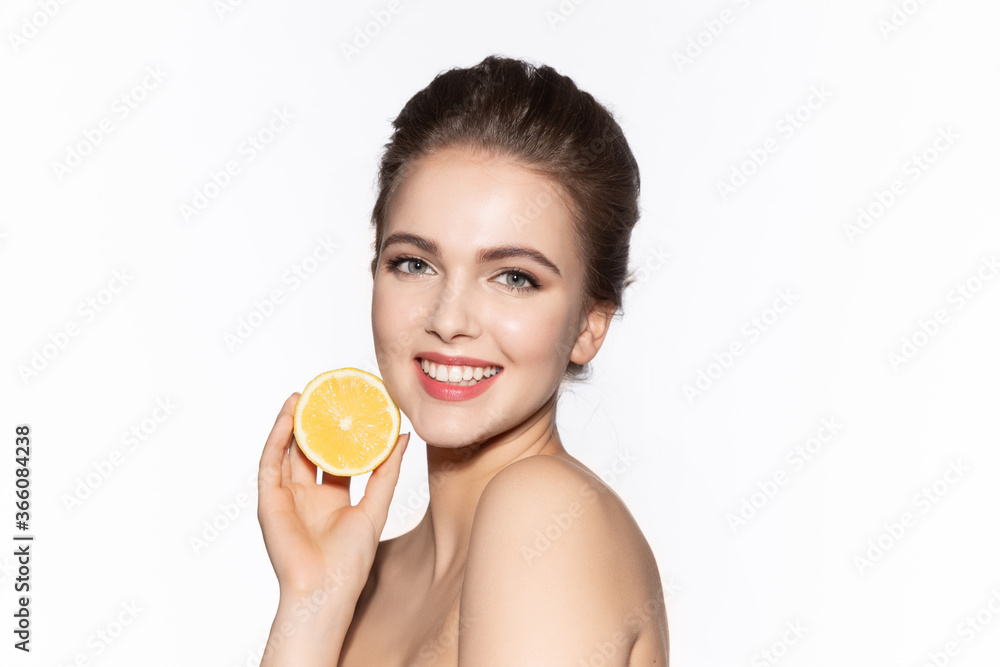 Woman holds cut juicy lemon near face skin. Woman holds cut juicy lemon near face skin.