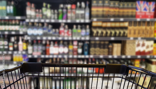 Abstract blurred image of alcohol store with trolley (Selective focused at shopping cart)