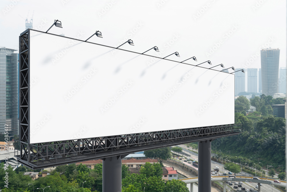 Obraz premium Blank white road billboard with KL cityscape background at day time. Street advertising poster, mock up, 3D rendering. Side view. The concept of marketing communication to promote or sell idea.