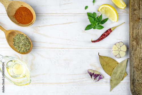 kitchen flat lay with spicy, lemon, garlic, oil, basil and cutting board. cooking light background