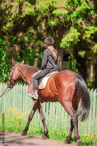 Girl riding her horse in a path in the park photo