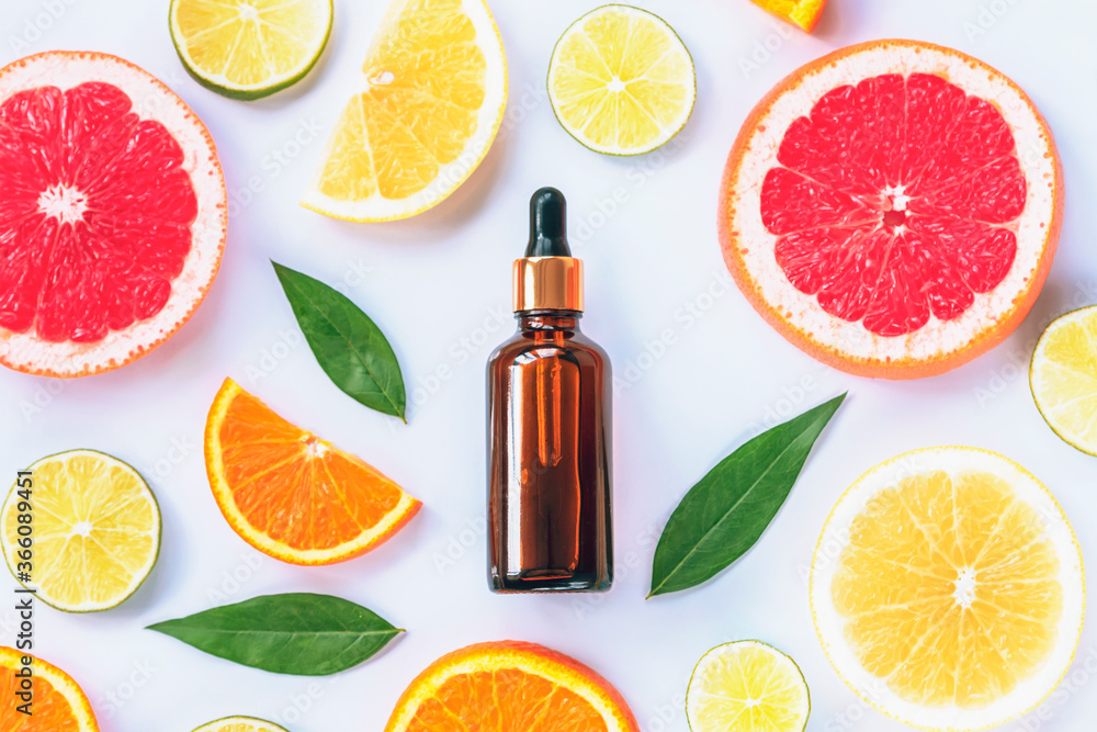 Glass bottle with cosmetic serum and sliced citrus fruits. Natural cosmetics with vitamin C. Top view, flat lay Glass bottle with cosmetic serum and sliced citrus fruits. Natural cosmetics with vitamin C. Top view, flat lay