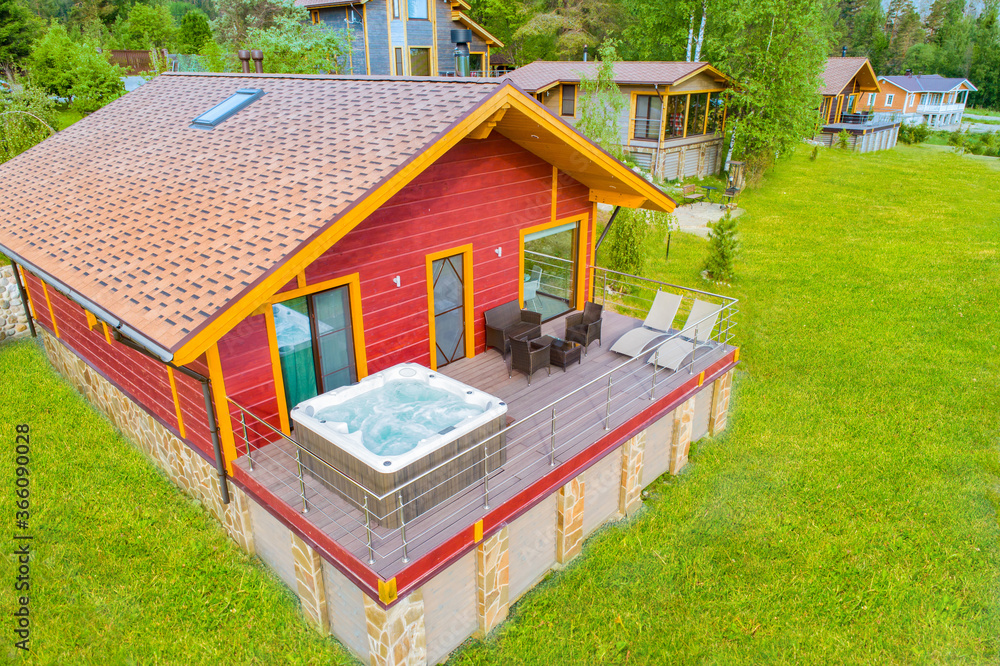Cottage village top view. House with bathtub for spa treatments. Hot tub is located on balcony