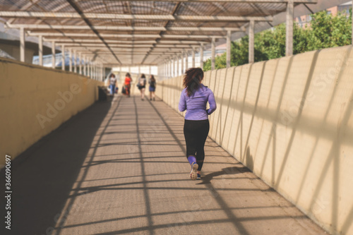 young woman runs along a pedestrian crosswalk, an active lifestyle concept