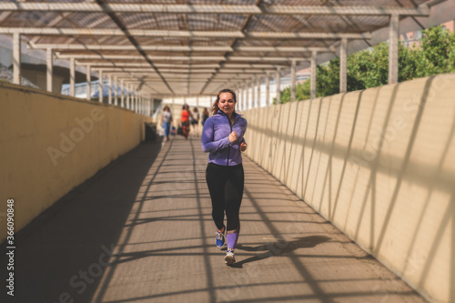 young woman runs along a pedestrian crosswalk, an active lifestyle concept