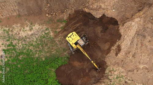 Working excavator in a clay open cast mine. Heavy industry from above. Industrial background from devastated landscape. Aerial view.