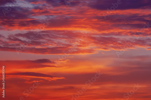 red orange purple colorful clouds in darkening sky at sunset © Enso