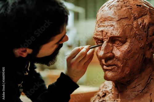 Focused sculptor finishing a clay head in an art studio