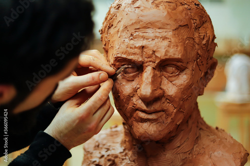 Close up of sculptor finishing a clay head eye in an art studio