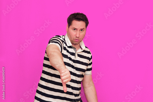 Caucasian man wearing casual striped t-shirt standing over isolated hot pink background shows various gestures.