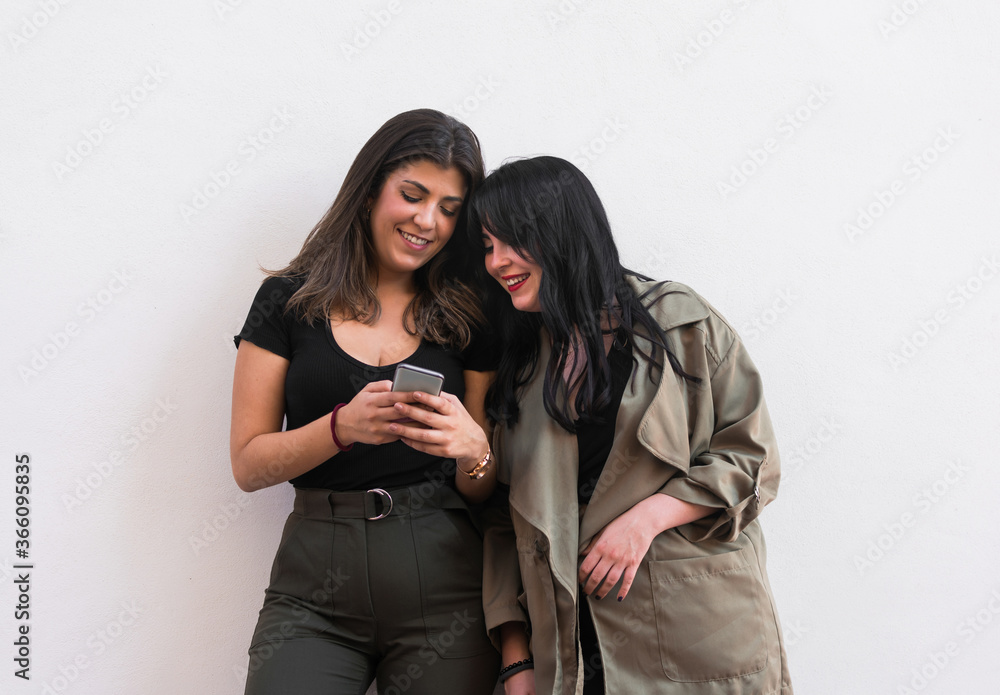 Two young women are using a smartphone on a white background Two young women are using a smartphone on a white background