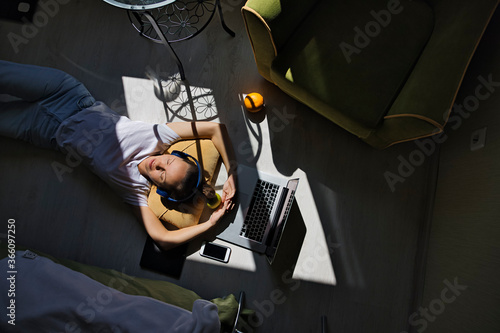 Young woman lying at the window at home with laptop photo